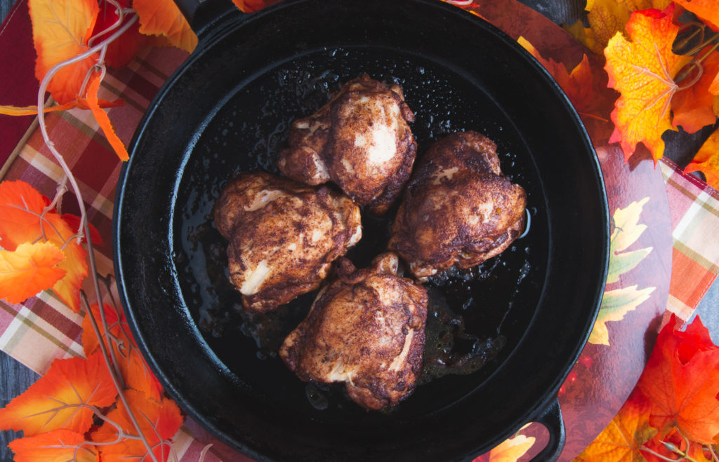 chicken thighs in cast iron skillet with fall decorations