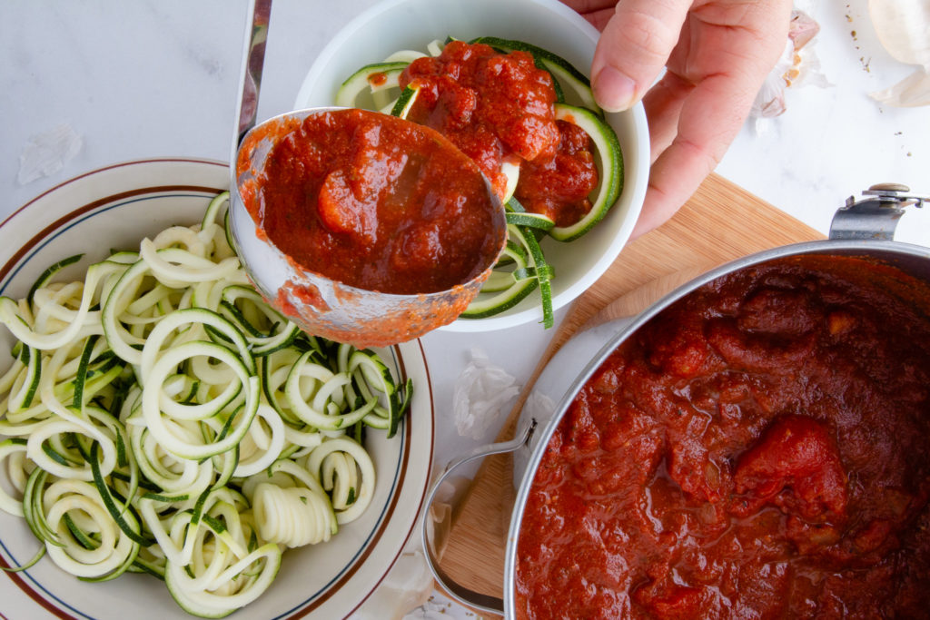 ladeling marinara over zoodles